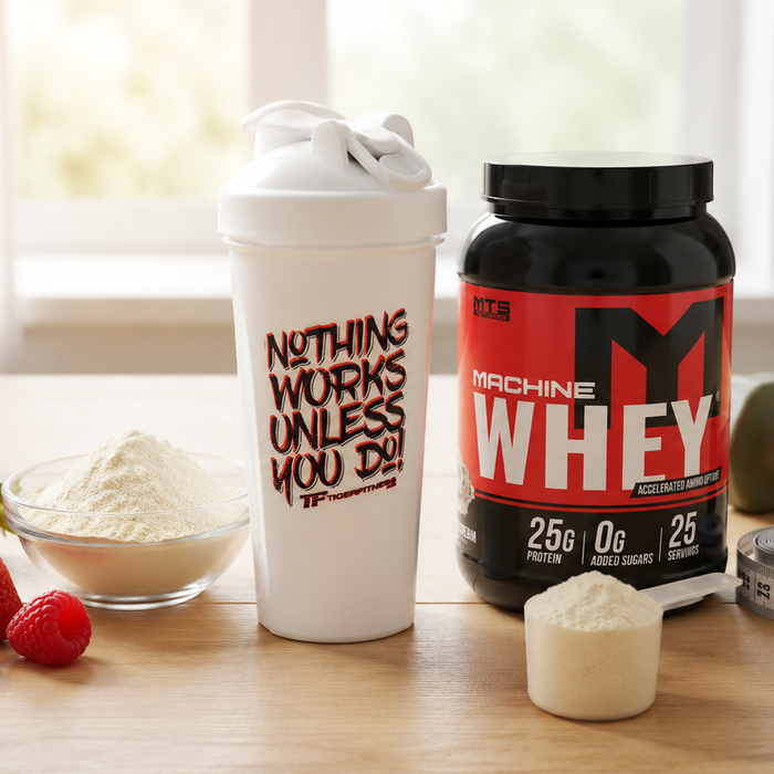 MTS Nutrition Machine Whey protein powder with Tiger Fitness shaker, fresh berries, and protein powder scoop on a countertop.
