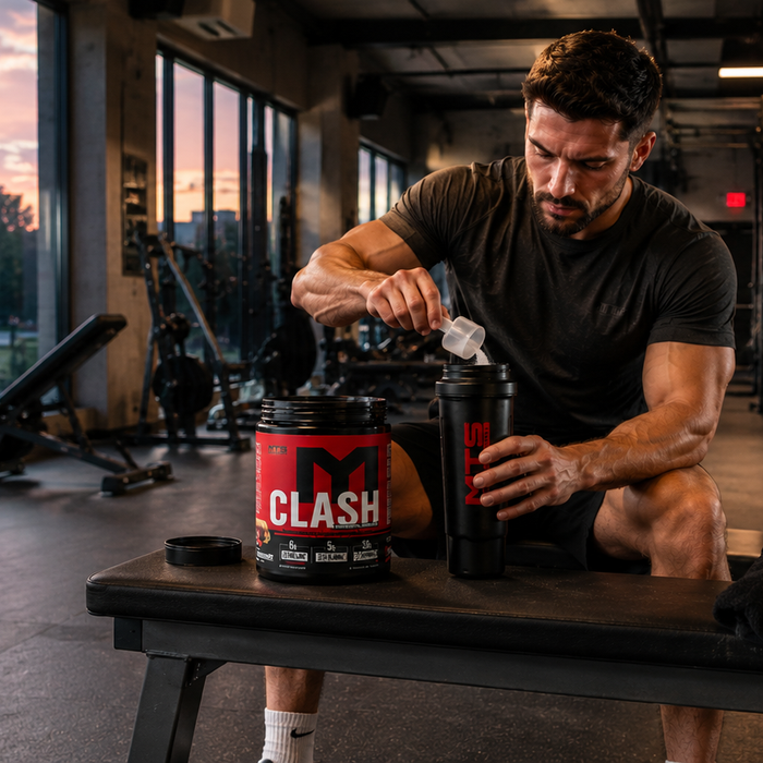 Man preparing MTS Clash pre-workout in a bright gym during an evening workout with a city sunset in the background.