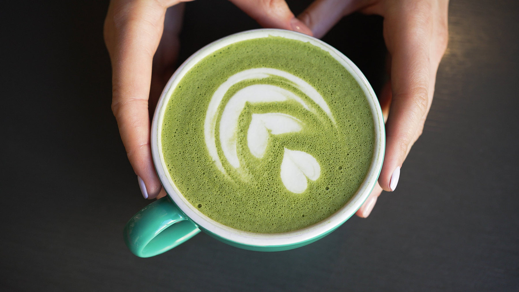 Hands preparing a cup of matcha green tea