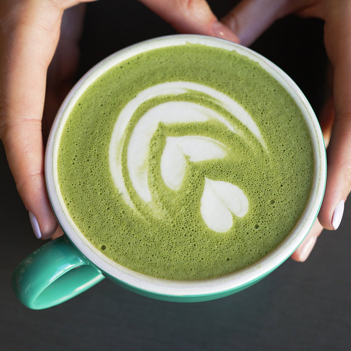 Hands preparing a cup of matcha green tea