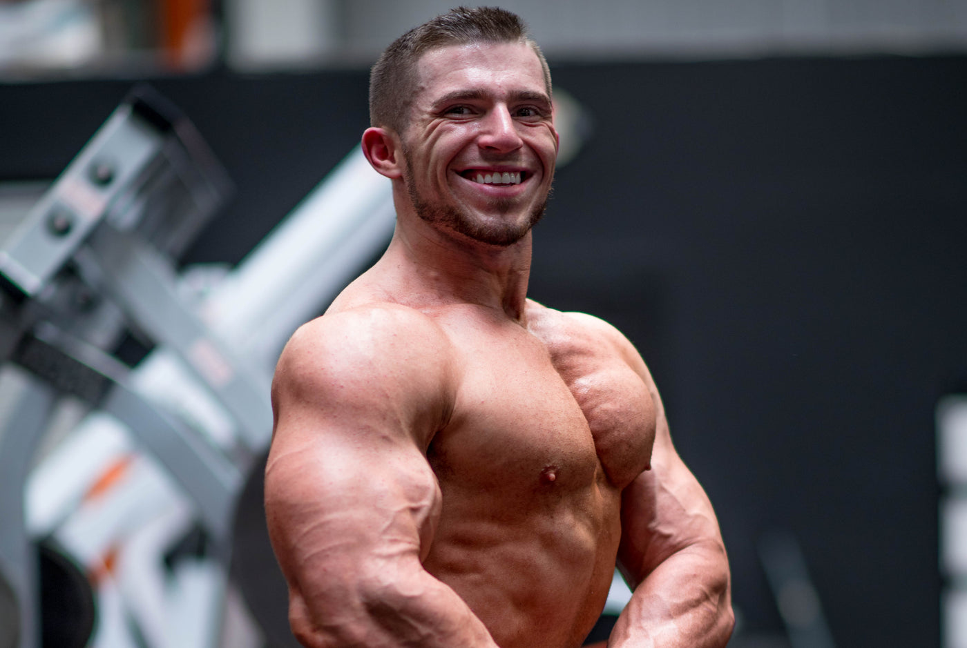 Zach Buckeye in a front physique pose in the gym, chest and torso lit from above, no equipment in frame.