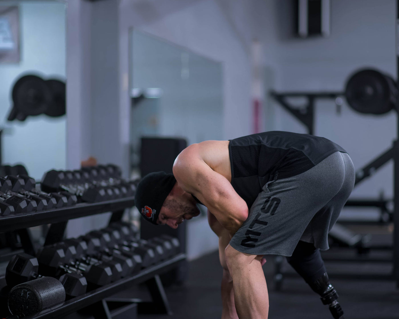 Louie Von Duhn bent over at the hip holding dumbbells, the torso position used for rear delt rows and reverse flyes.
