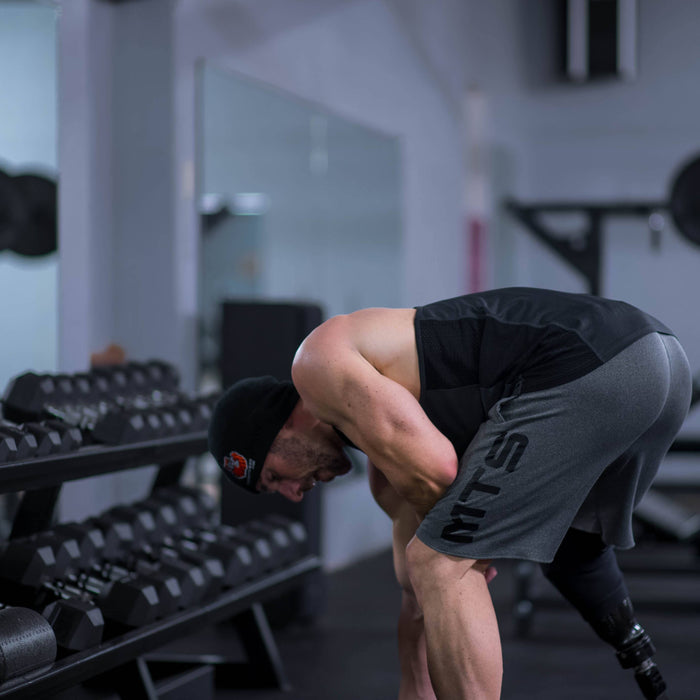 Louie Von Duhn bent over at the hip holding dumbbells, the torso position used for rear delt rows and reverse flyes.
