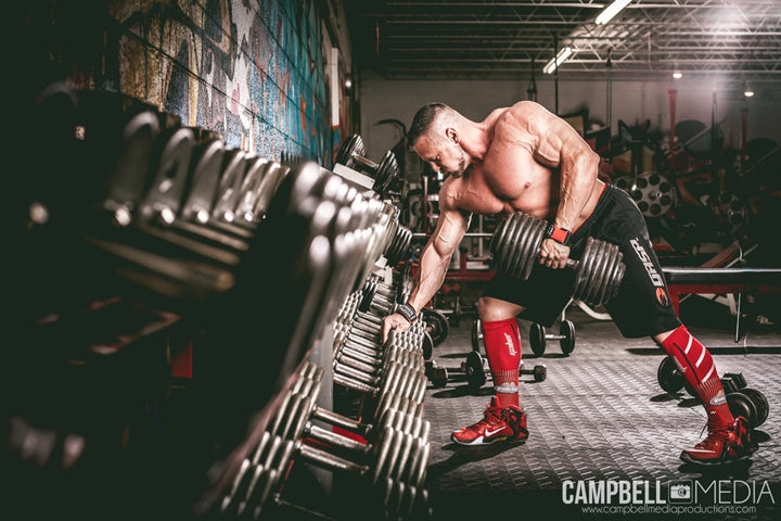 Marc Lobliner rowing a single dumbbell toward his hip with a flat back during a full body session using one fixed pair