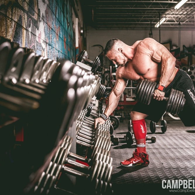 Marc Lobliner rowing a single dumbbell toward his hip with a flat back during a full body session using one fixed pair