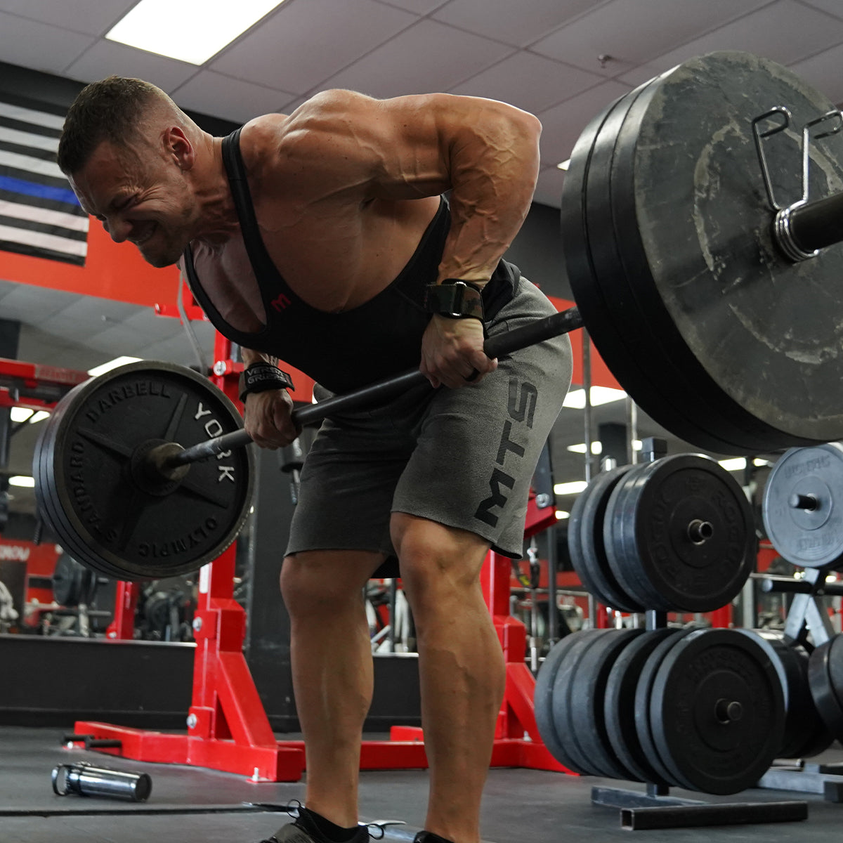 Marc Lobliner rowing a loaded barbell to his waist with a hinged torso and braced back in a gym setting