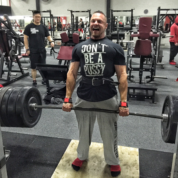 Marc Lobliner pulling a loaded barbell from the floor, hips and shoulders rising together as the bar leaves the platform