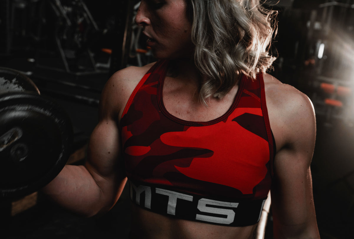 Female athlete Ireland Beatty performing a cable tricep pushdown in the gym, the kind of machine and cable work this Planet Fitness plan for women is built on