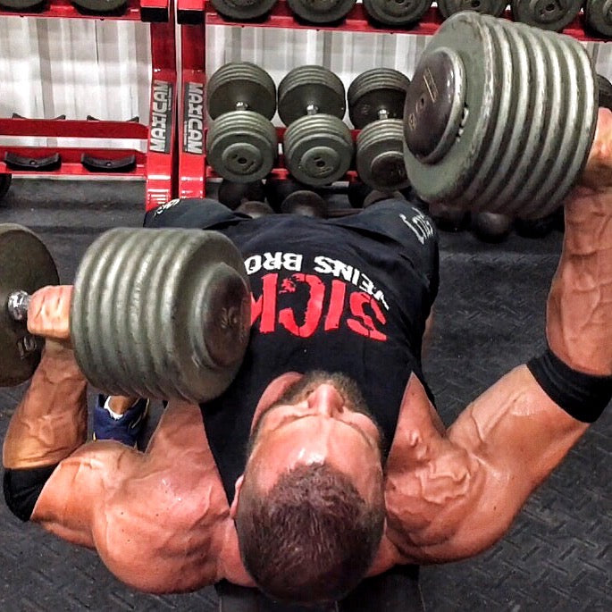 Marc Lobliner pressing a pair of dumbbells from a flat bench during an upper body training session in the gym