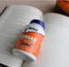 NOW Foods DMAE 250 mg bottle placed on an open book, highlighting healthy brain function support, 100 veg capsules