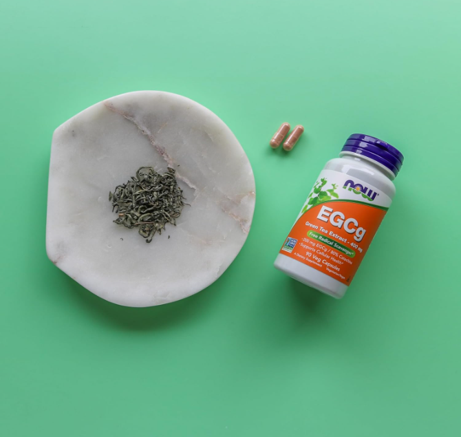 NOW Foods EGCg Green Tea Extract 400 mg bottle with loose green tea leaves and capsules lifestyle image
