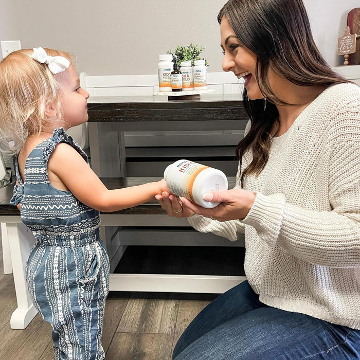 Parent giving NOW Kids Kid Cal chewable calcium tablet to child at home